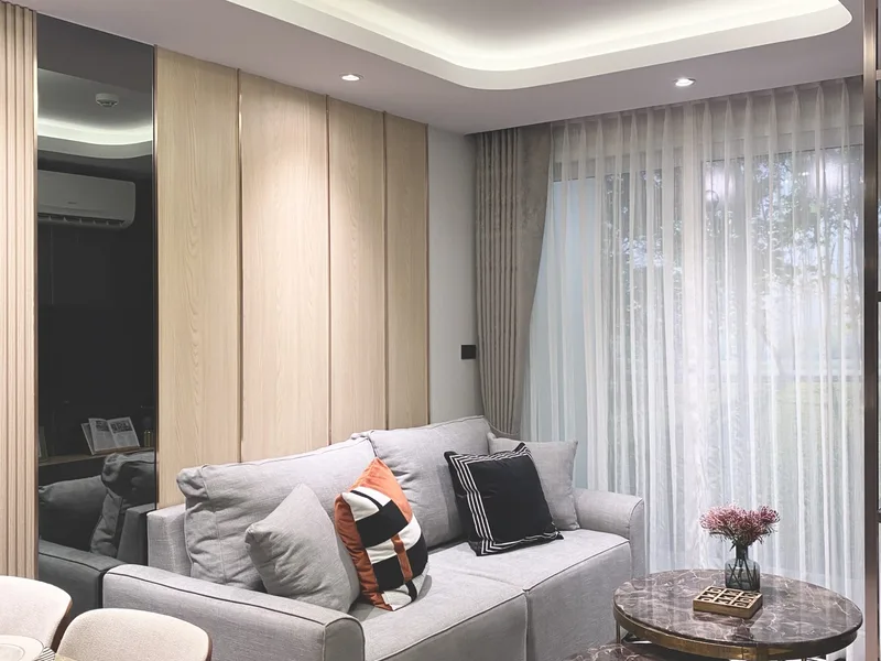 A living room with sofa and windows in the Pristine Park III show unit, Pattaya